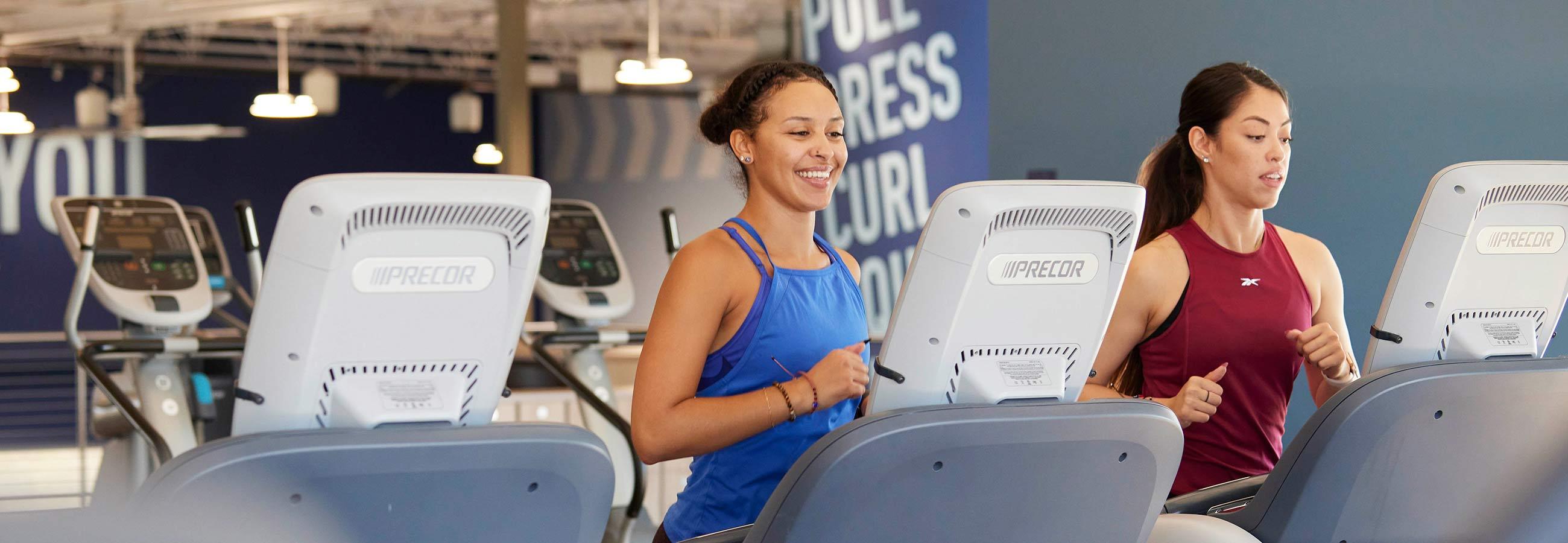 two women running on treadmills
